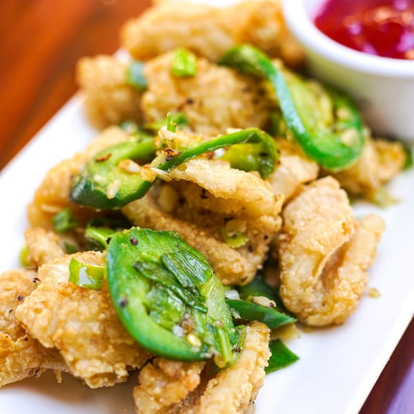 Crispy fried calamari with green peppers and a side of red dipping sauce.