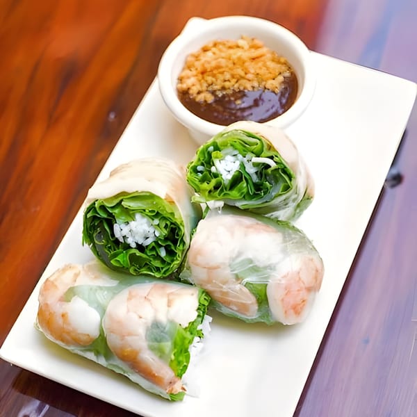 Four fresh Vietnamese spring rolls with shrimp, lettuce, and rice vermicelli, served with peanut sauce.